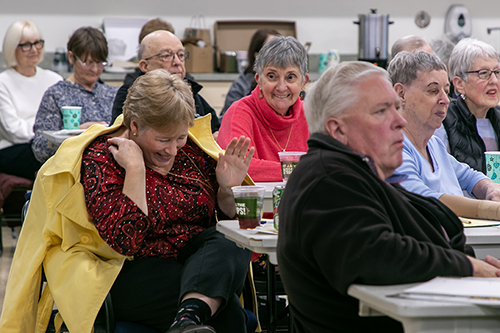A group of older adults laughing and smiling in a town hall