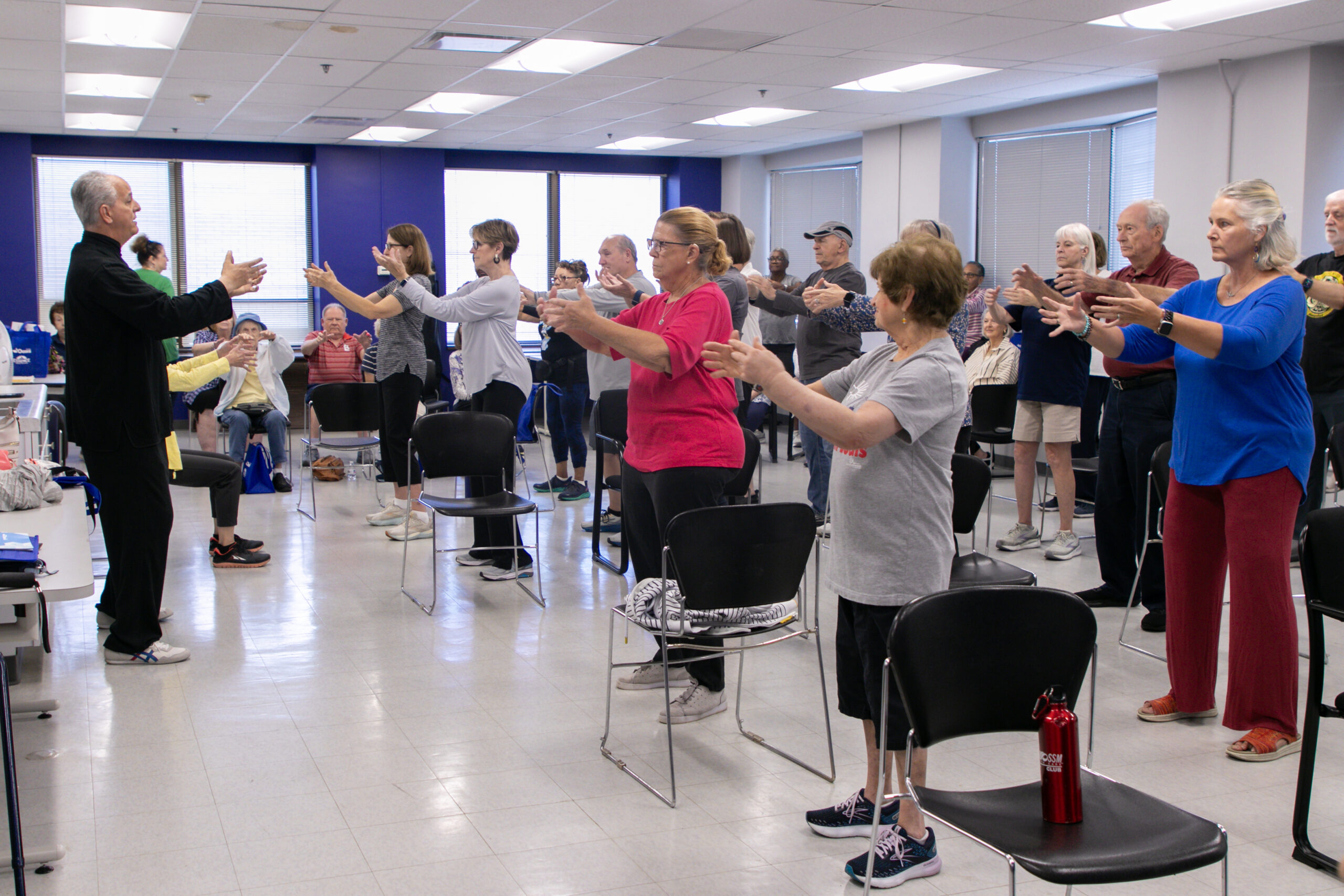 A group of older adults practicing Tai Chi in an Oasis classroom