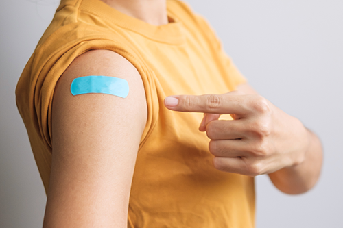 photo of person pointing to band aid at vaccine site